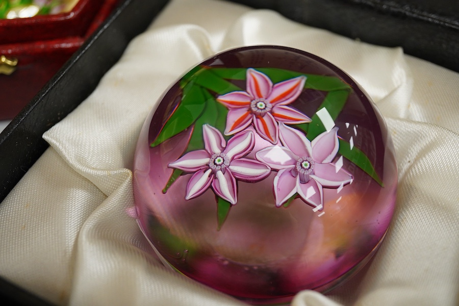 Two Perthshire lamp work glass paperweights, fruit weight, 52/350, rose and bud weight, 69/300 together with a John Deacons bouquet on a ruby base paperweight, edition of 101 (3)